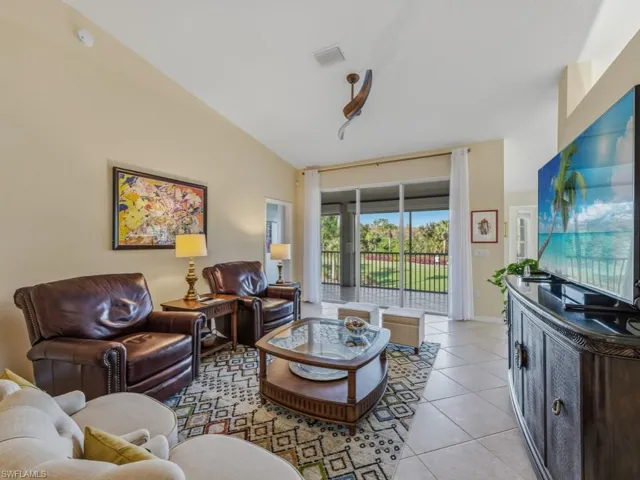 Living room with light tile patterned flooring and vaulted ceiling