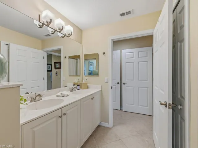 Full bath with double vanity and light tile patterned floors