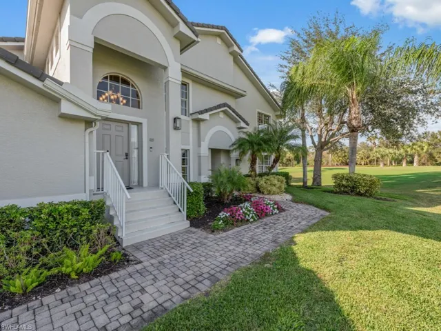 View of exterior entry with a yard and stucco siding