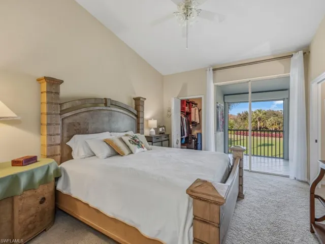 Bedroom with a walk in closet, light colored carpet, access to outside, ceiling fan, and vaulted ceiling