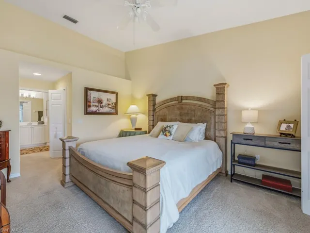 Bedroom featuring ceiling fan, light colored carpet, and ensuite bath