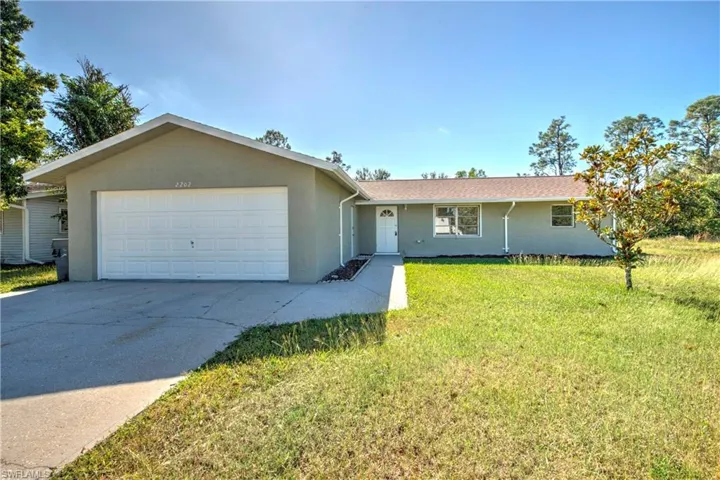 Ranch-style home featuring a front lawn and a garage