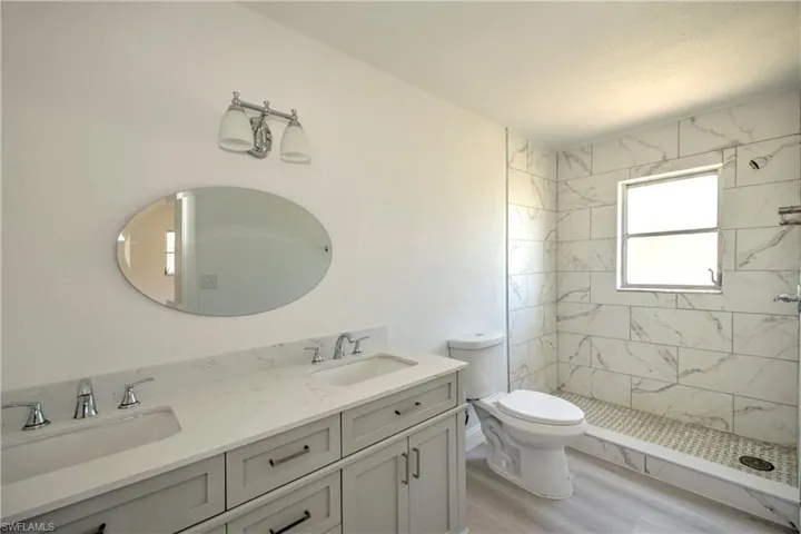 Bathroom featuring hardwood / wood-style floors, toilet, a tile shower, and vanity