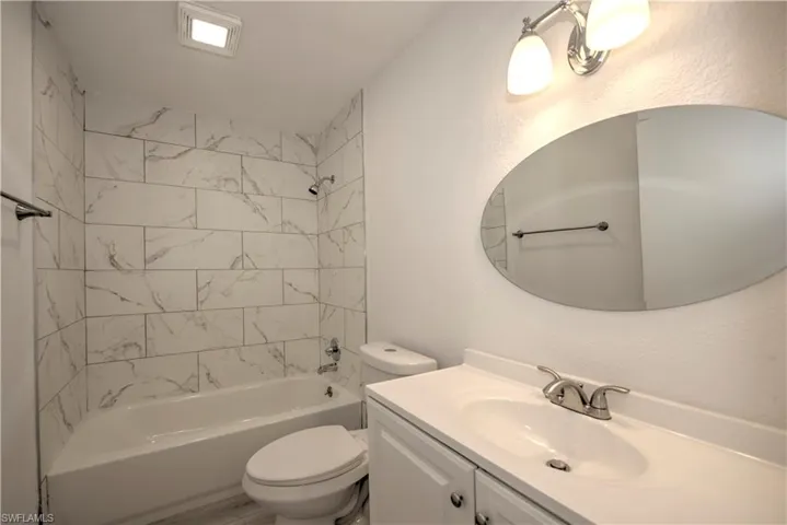 Full bathroom featuring toilet, vanity, and tiled shower / bath