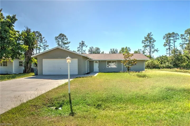 Single story home with a garage and a front lawn