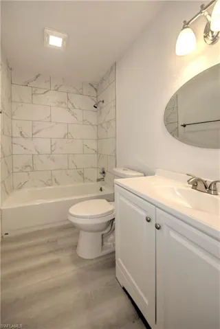Full bathroom with wood-type flooring, vanity, toilet, and tiled shower / bath