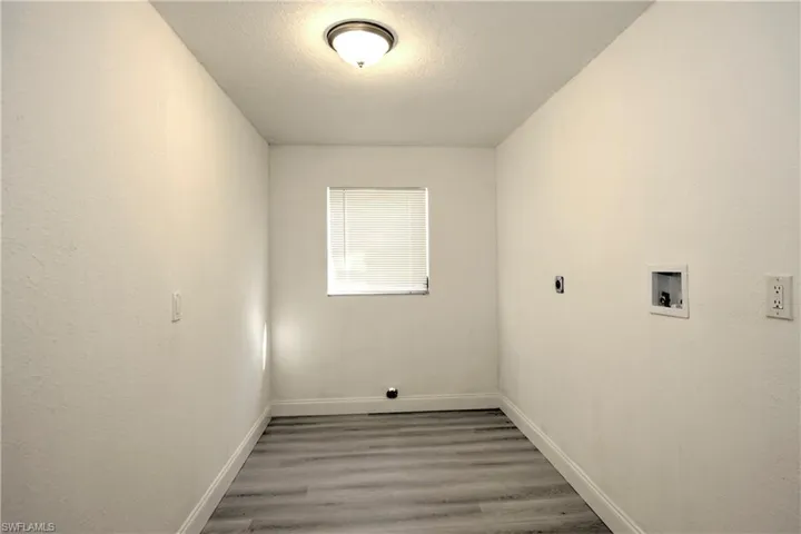 Clothes washing area featuring hookup for a washing machine, a textured ceiling, and hardwood / wood-style flooring