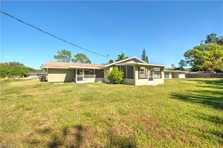 Rear view of property featuring a sunroom and a yard