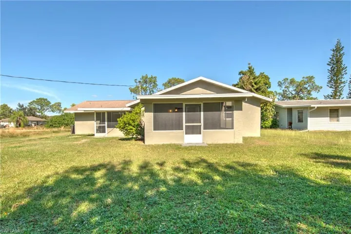 Rear view of property with a sunroom and a yard