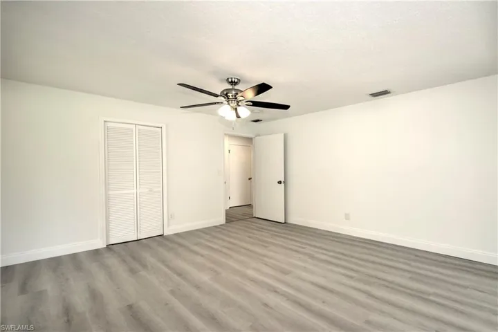 Unfurnished bedroom with a textured ceiling, a closet, light hardwood / wood-style floors, and ceiling fan