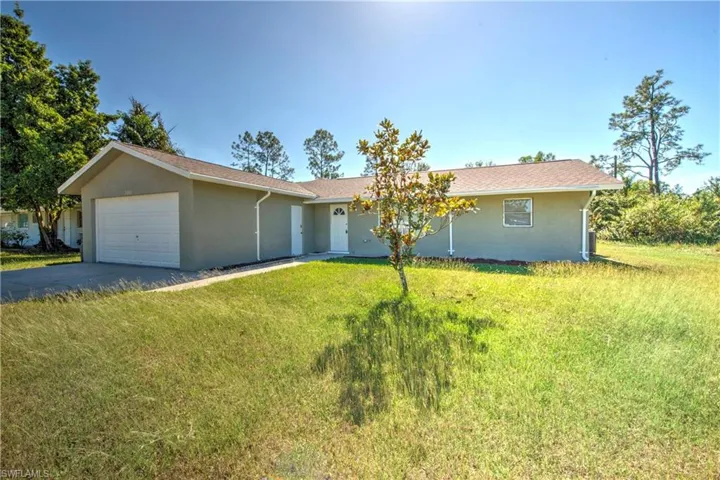 Ranch-style house featuring a garage and a front lawn
