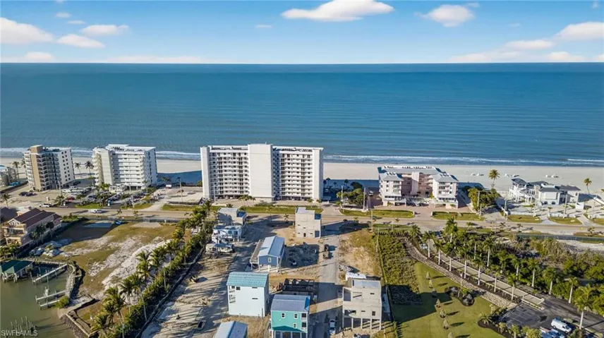 Aerial perspective of coastal residential property with proximity to the shoreline, sandy beach access, and natural palm tree landscaping