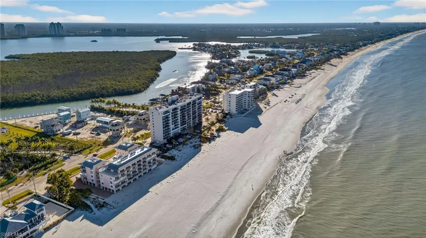 Aerial perspective of coastal property featuring direct oceanfront access, sandy beach frontage, and surrounding estuary waterways