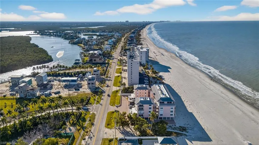 Aerial perspective of coastal landscape featuring direct ocean frontage, sandy beach access, and proximity to tidal waterway ecosystems