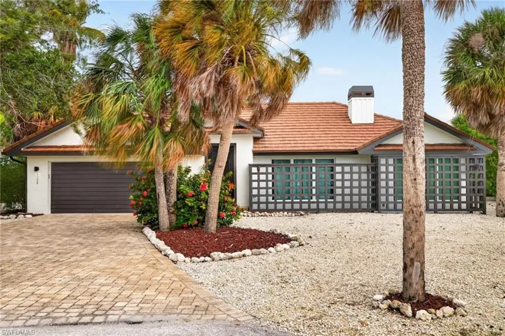 Exterior with a tile roof, white stucco facade, and a dark garage door