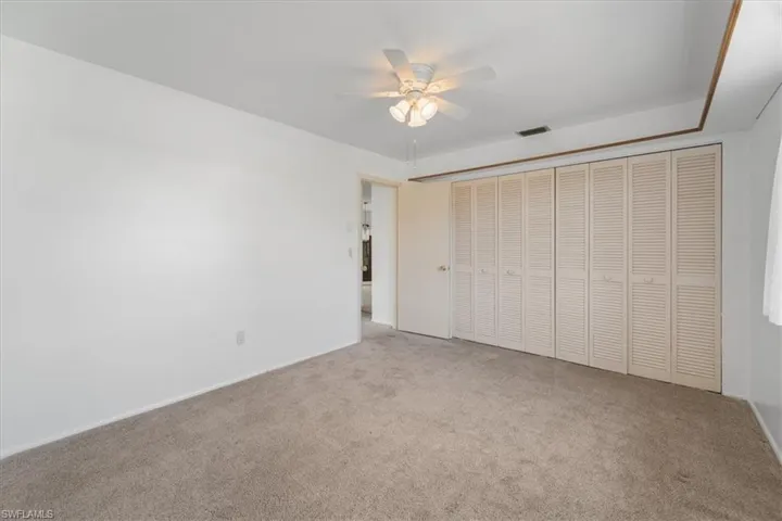 Unfurnished bedroom featuring visible vents, carpet floors, and ceiling fan