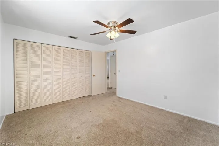 Unfurnished bedroom featuring a closet, visible vents, a ceiling fan, and carpet floors