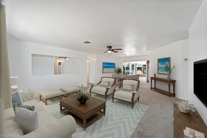 Carpeted living room with visible vents and ceiling fan with notable chandelier
