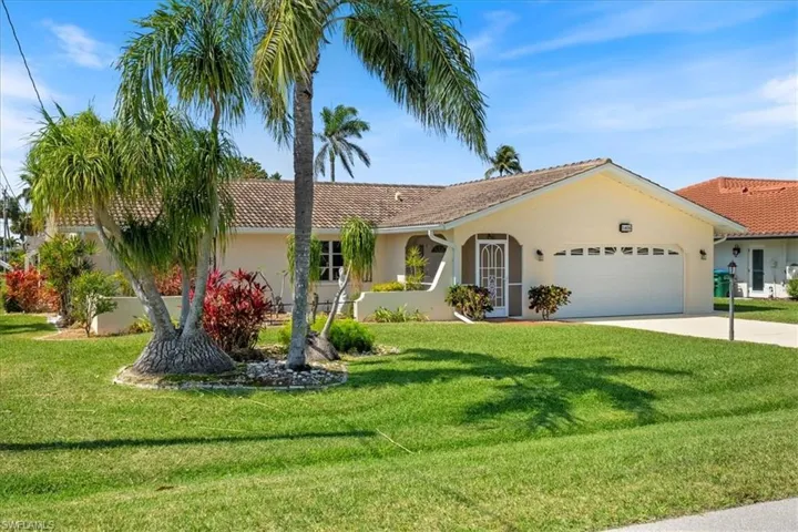 Single story home featuring stucco siding, driveway, a front lawn, and an attached garage