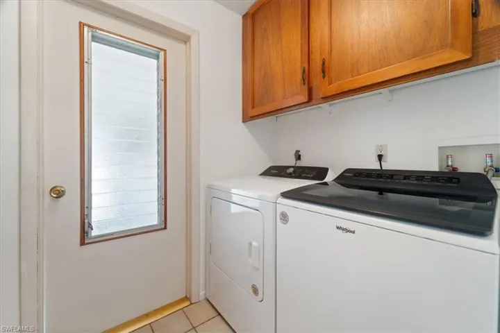 Washroom with light tile patterned floors, cabinet space, and washing machine and dryer