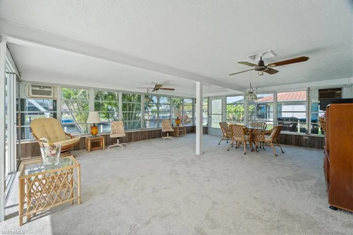Unfurnished sunroom featuring a ceiling fan and a wall mounted air conditioner