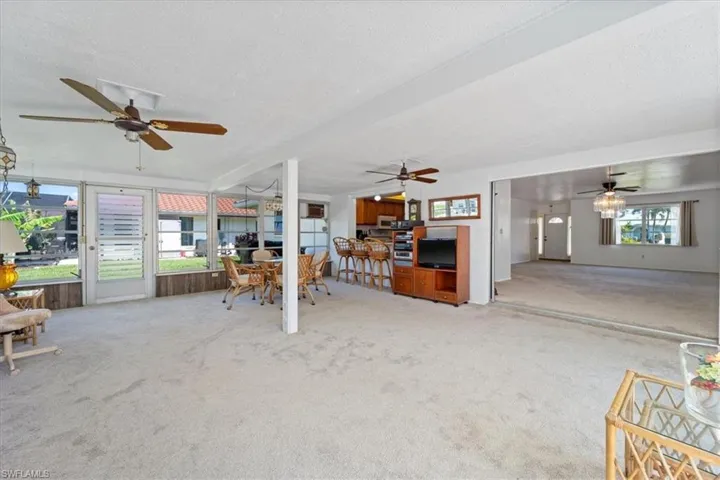 Unfurnished living room featuring ceiling fan, carpet floors, and a textured ceiling