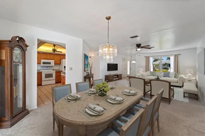Dining room with light tile patterned floors, visible vents, light carpet, and a ceiling fan