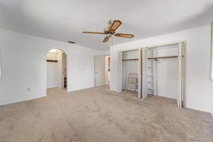 Unfurnished bedroom with visible vents, multiple closets, ornamental molding, arched walkways, and carpet flooring