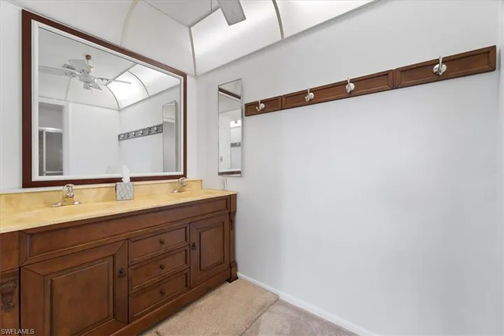 Full bath featuring double vanity, a ceiling fan, baseboards, and a sink