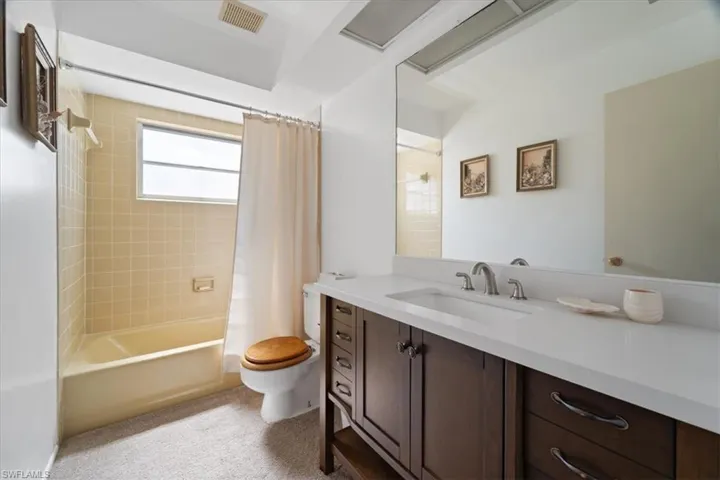 Full bathroom featuring vanity, toilet, shower / bath combo, and visible vents