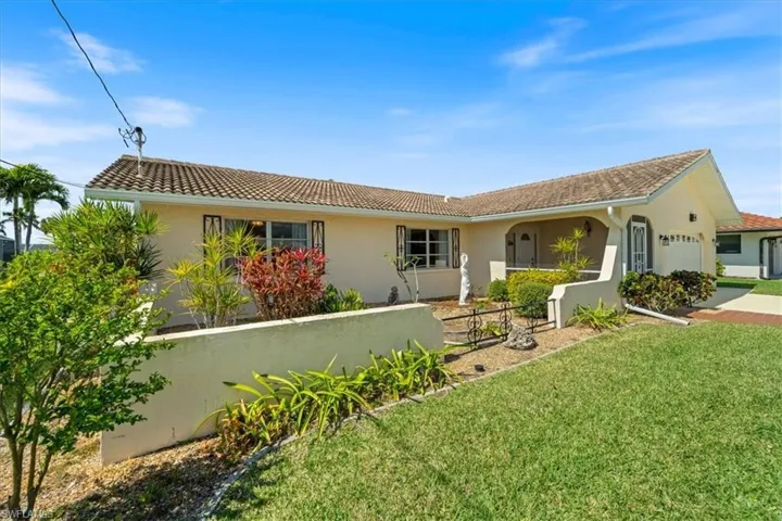 View of front facade with fence, a tile roof, a front yard, stucco siding, and a garage