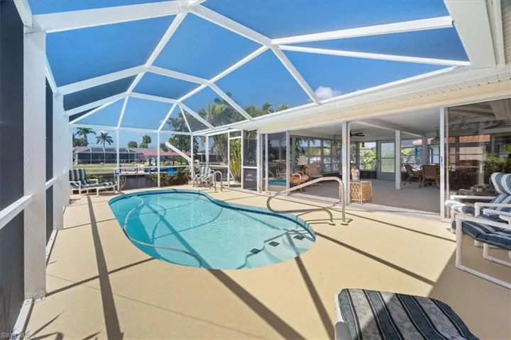Pool featuring glass enclosure and a patio