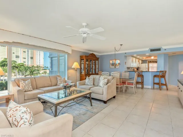 Tiled living room with ceiling fan with notable chandelier, crown molding, and a wealth of natural light