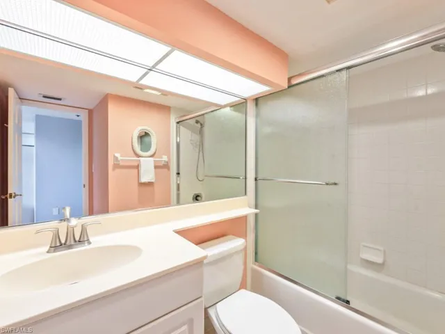 Full bathroom featuring combined bath / shower with glass door, vanity, and toilet