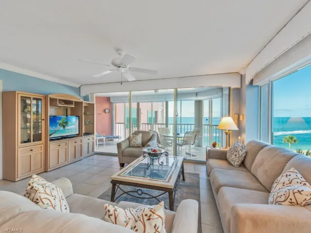 Tiled living room with crown molding, ceiling fan, and a water view