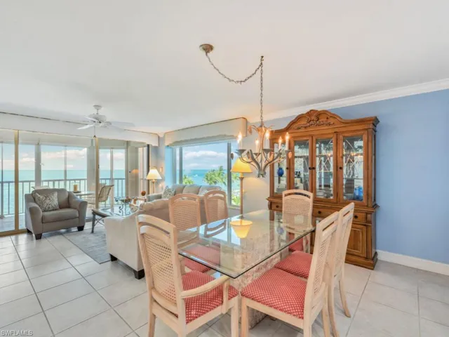 Dining room featuring crown molding, light tile flooring, a water view, and ceiling fan with notable chandelier