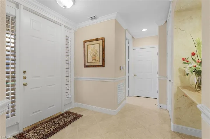Entrance foyer featuring light tile patterned floors, ornamental molding, and recessed lighting