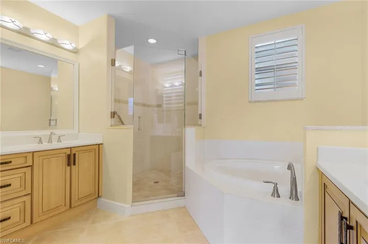 Bathroom featuring vanity, a shower stall, a bath, light tile patterned floors, and recessed lighting