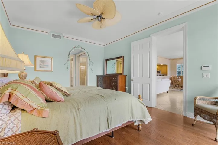 Bedroom with crown molding, wood finished floors, and ceiling fan