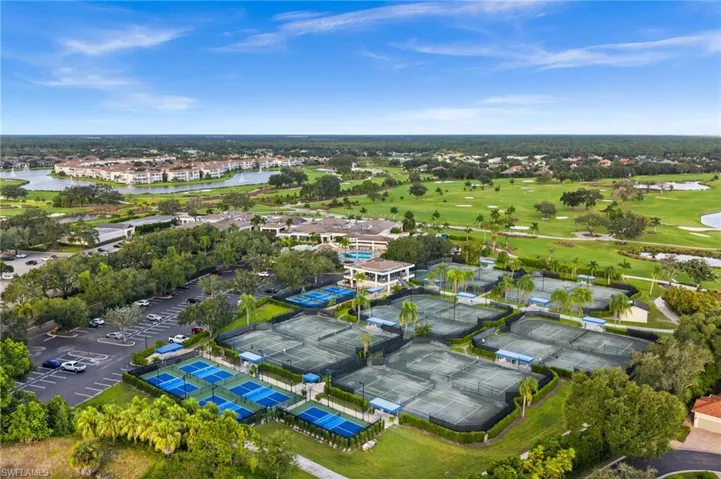 Aerial perspective featuring multiple tennis courts, hard-surface sport courts, an open-air clubhouse pavilion, and paved parking