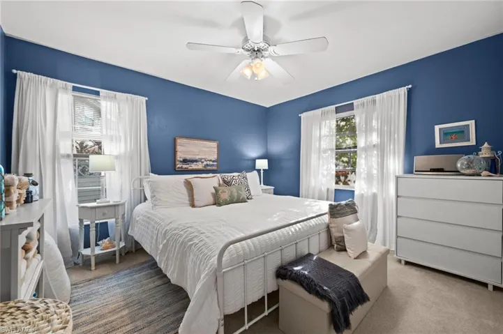 Spacious room featuring dual windows with clean-lined trim and a central white ceiling fan with integrated lighting
