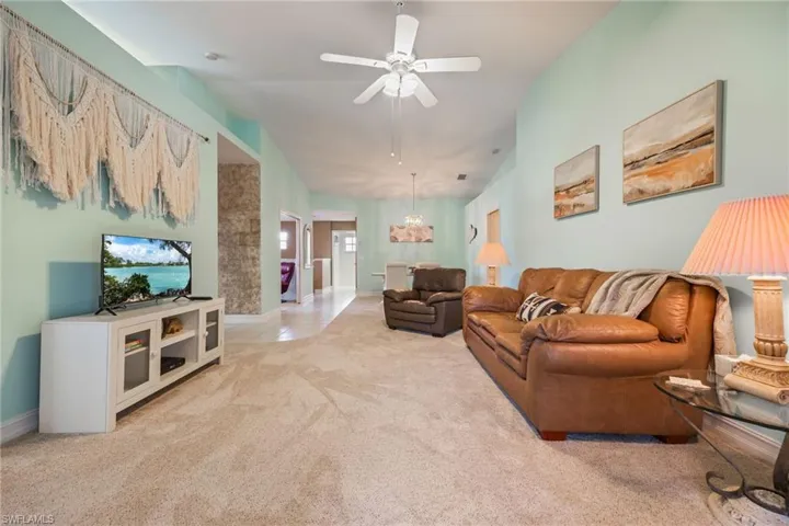 Carpeted living room with a ceiling fan and vaulted ceiling