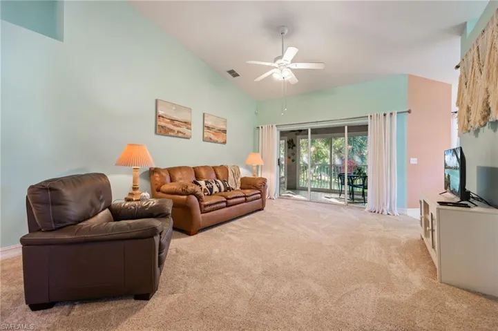 Living area featuring carpet flooring, ceiling fan, and high vaulted ceiling