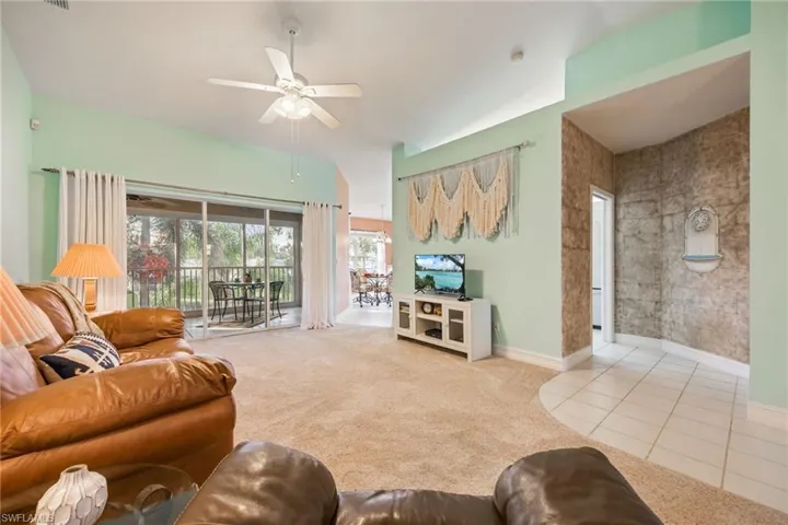 Carpeted living room featuring a ceiling fan and tile patterned floors