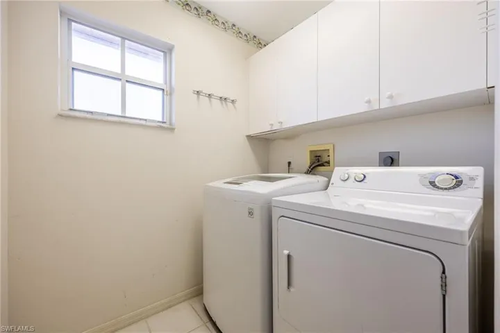Laundry area featuring cabinet space, washer and dryer, and light tile patterned floors
