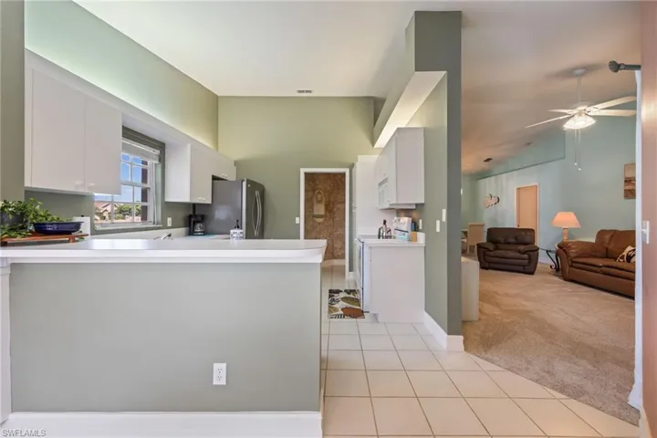 Kitchen with refrigerator, light tile patterned flooring, light carpet & light countertops