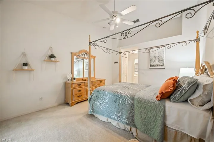 Carpeted bedroom featuring ceiling fan and high vaulted ceiling