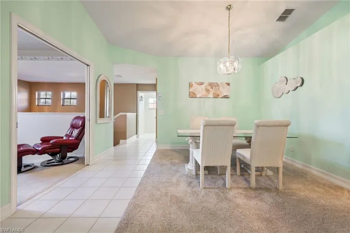 Carpeted dining area with a chandelier, plenty of natural light, and tile patterned flooring