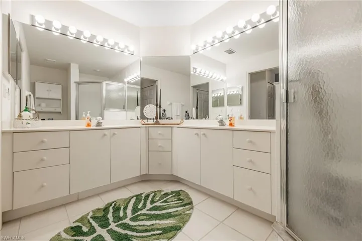 Bathroom with tile patterned flooring, double vanity, and a stall shower