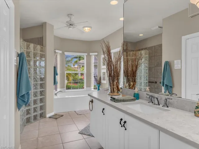 Bathroom featuring vanity, tile patterned floors, ceiling fan, and shower with separate bathtub